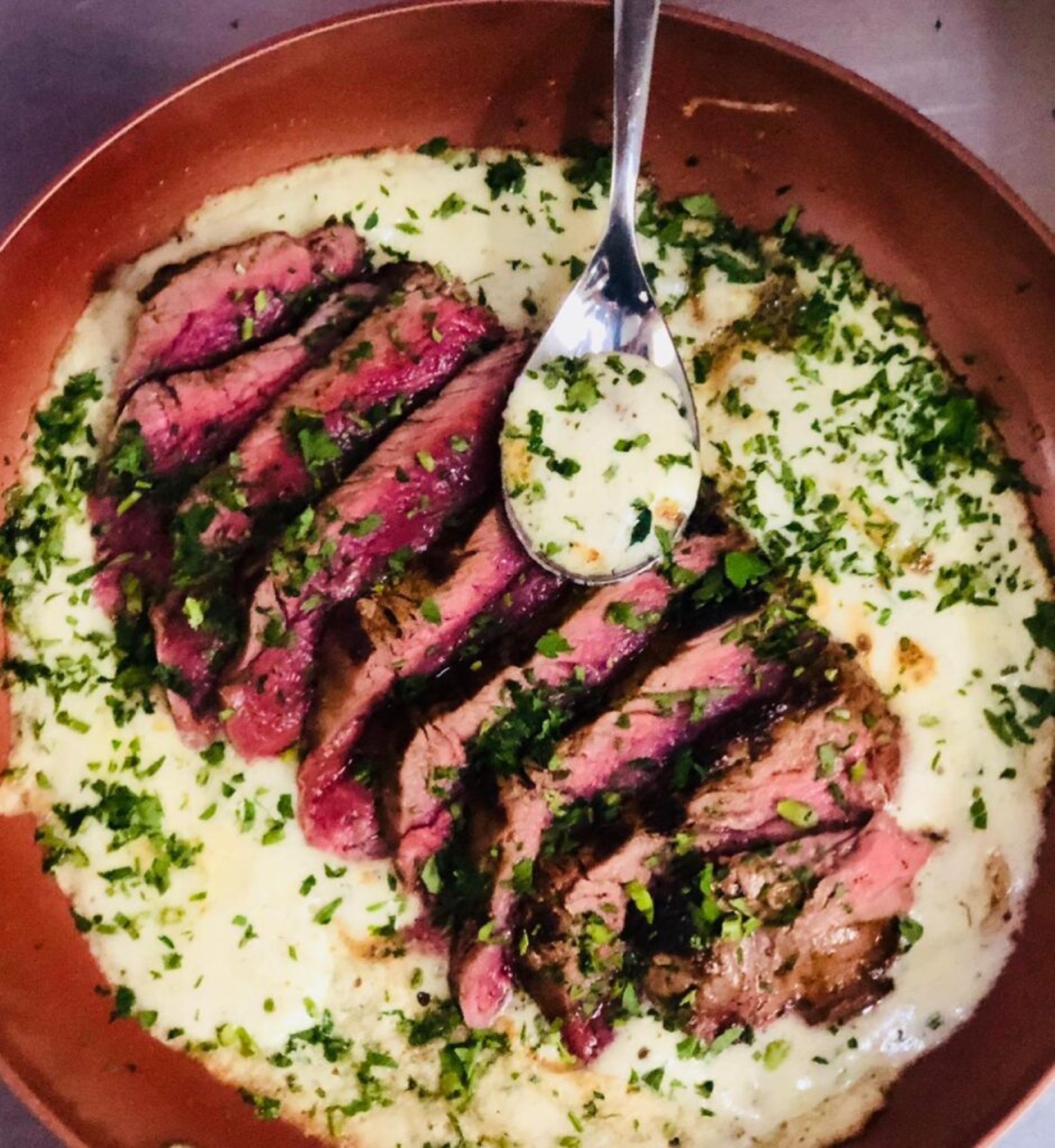 Aufgeschnittenes Fleisch auf cremiger Sauce mit Petersilie
