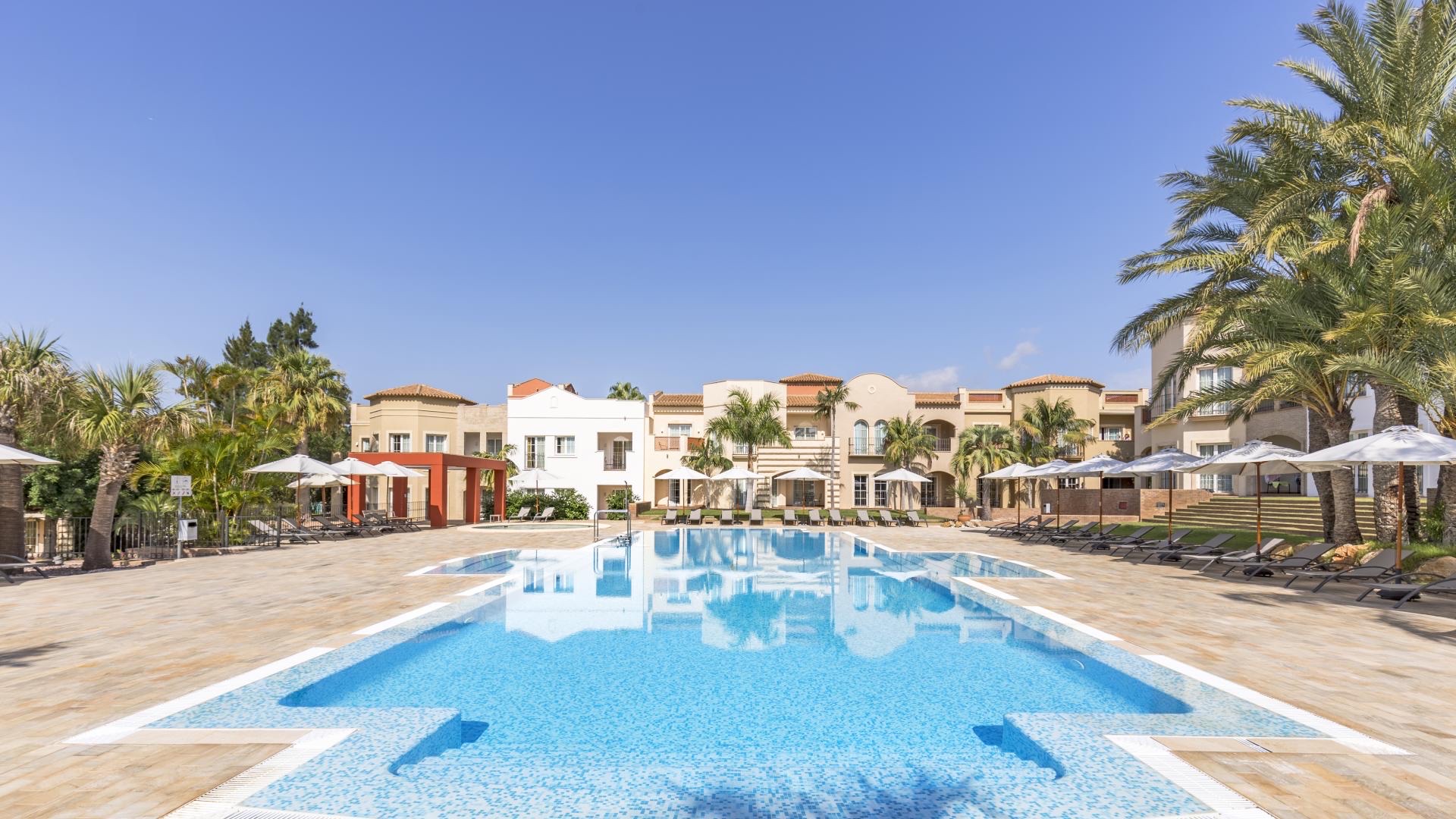 Außenpool des Resorts mit Liegen und Palmen
