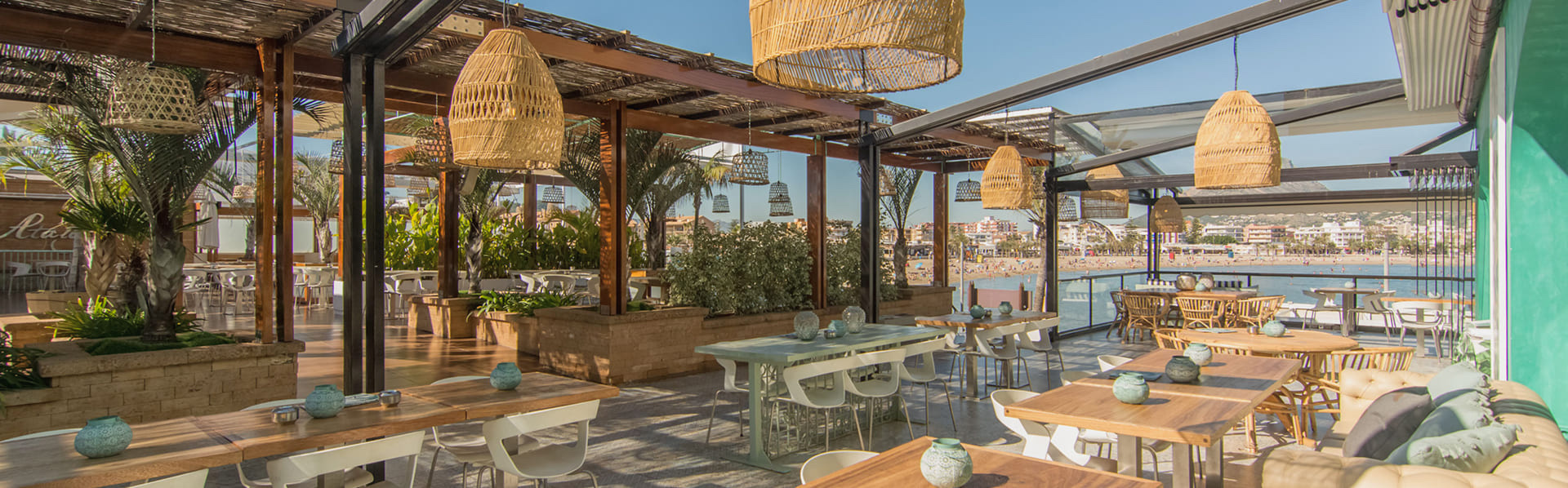 Überdachte Terrasse mit Korblampen und Blick auf den Strand