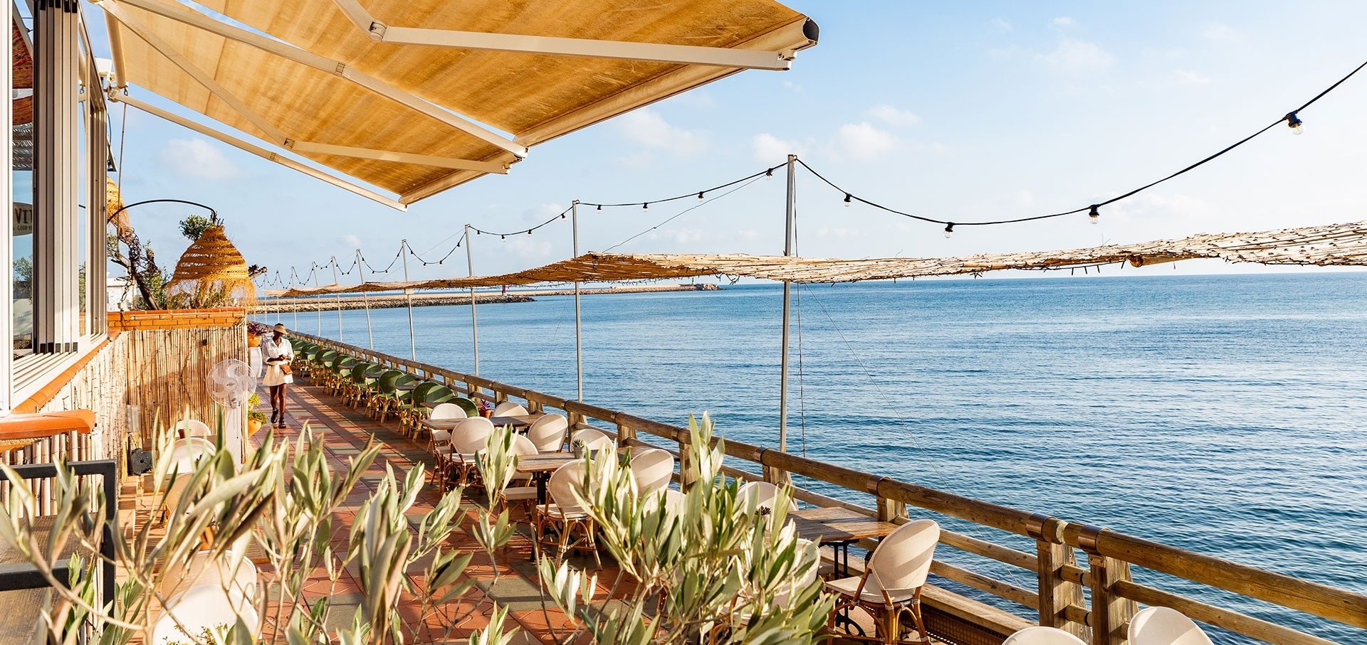 La terrasse de Mala Vita sur la mer dans la Marina de Dénia, avec ses stores et ses guirlandes lumineuses