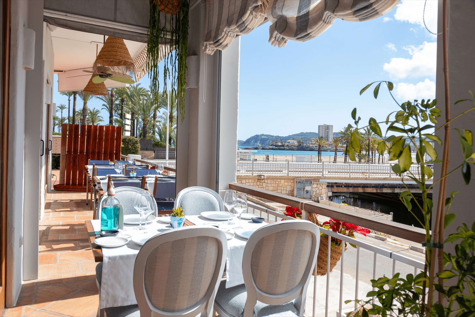 Terrasse mit gedeckten Tischen und Blick auf Promenade und Strand