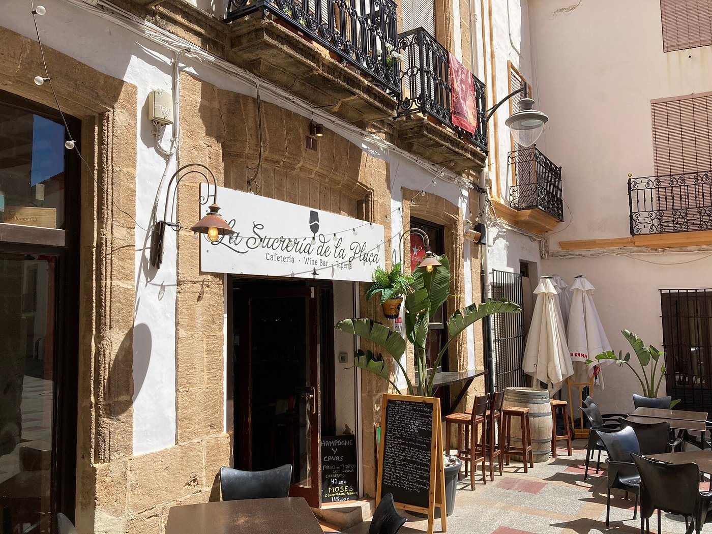 Façade en pierre de La Sucrería de la Plaça et sa terrasse dans une rue ensoleillée de la vieille ville de Jávea