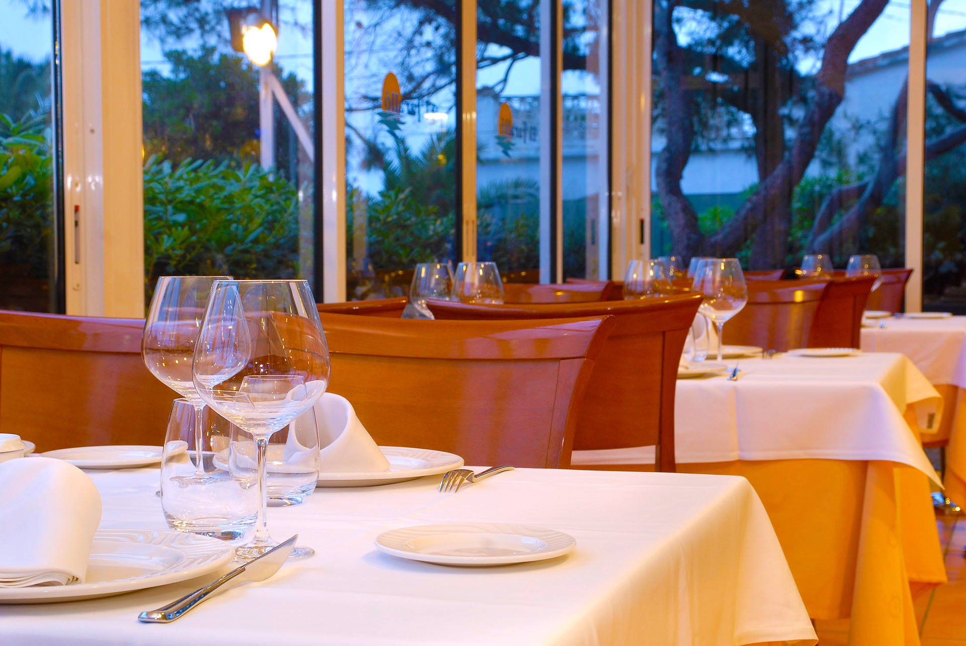 Salle vitrée aux tables nappées de blanc au crépuscule