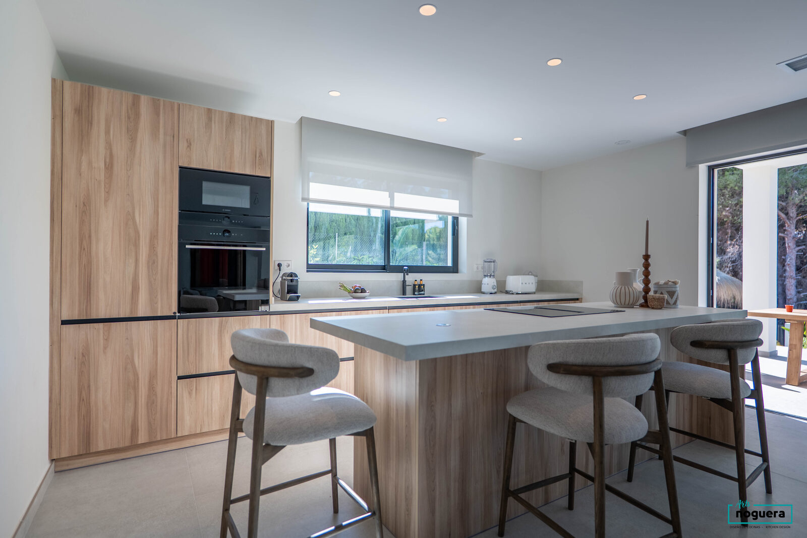 Küche mit Insel und Barhockern, Holzfronten und Backofenschrank