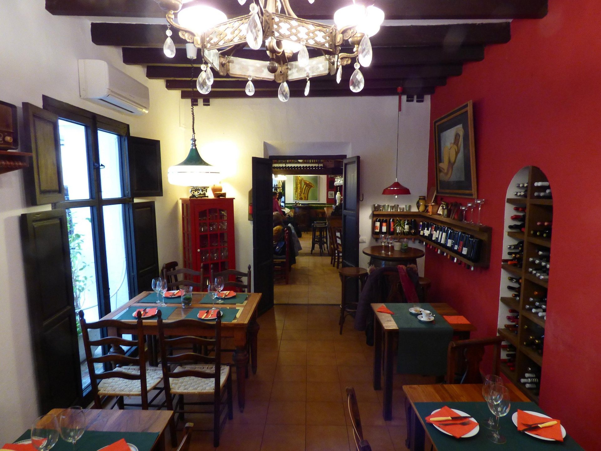 La Rebotica's dining room with a red wall, wooden beams, a chandelier and a wine rack