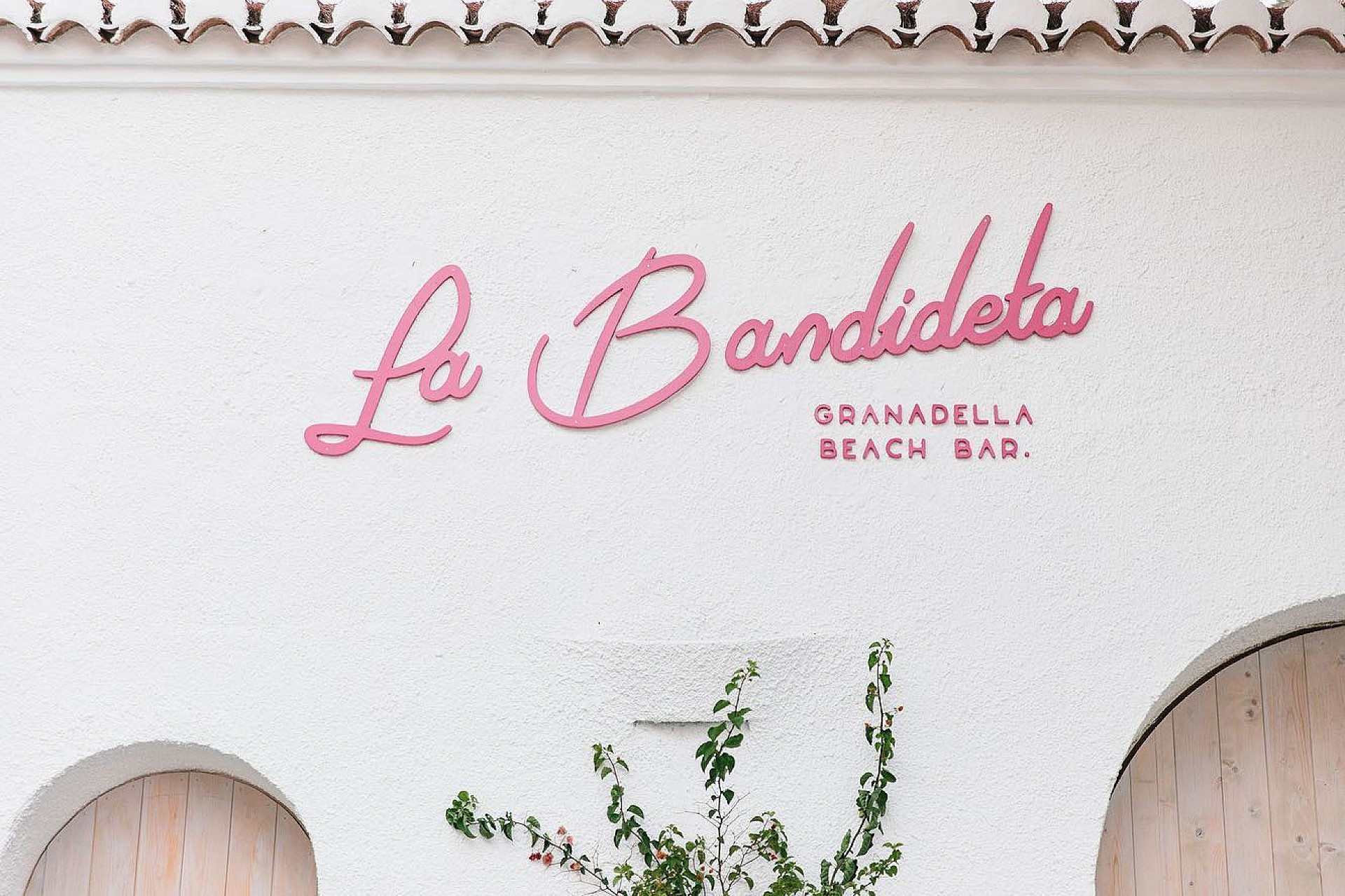 La façade blanche de La Bandideta et son enseigne rose