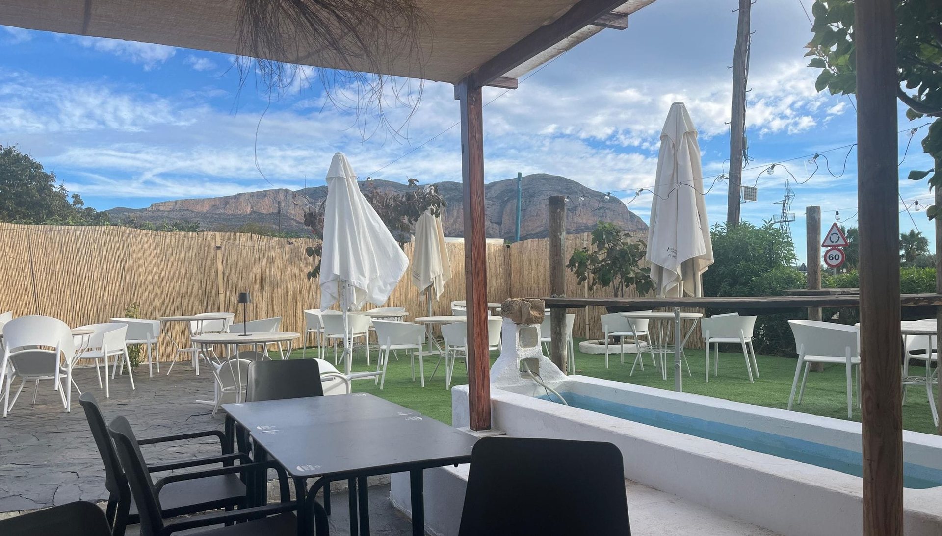 La terrasse de Cuadros 45, avec pelouse, tables blanches et le Montgó en toile de fond